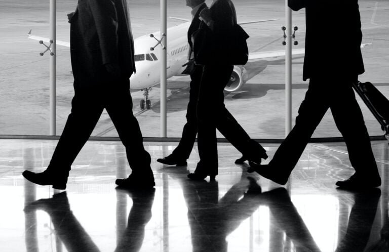 Three businessmen preparing for business travel to South Korea walking down the airport.