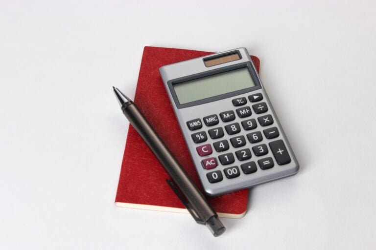 Image of a calculator on the top of a red notebook used for keeping track of taxes.
